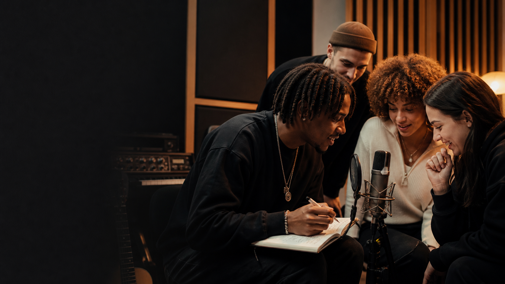 A group sharing ideas and writing beside a microphone in a music studio.